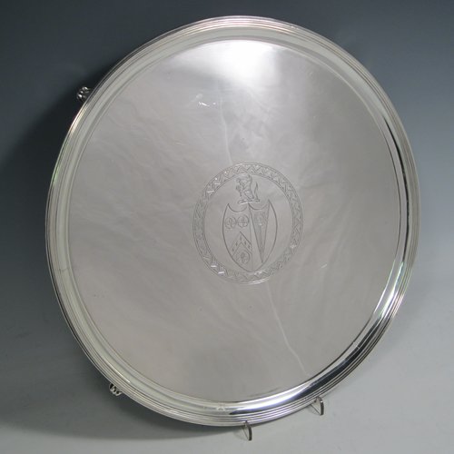 A handsome Antique Georgian Sterling Silver salver, having an applied reeded border, a plain ground with a hand-engraved armorial central crest, and sitting on four cast reeded feet. This elegant antique silver salver was made by Thomas Wallis II of London in 1796. The dimensions of this fine hand-made antique silver salver are diameter 33 cms (13 inches), and it weighs approx. 1,062g (34.3 troy ounces).   