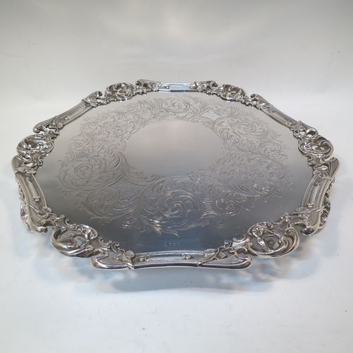 A very pretty Antique Victorian Silver Plated large salver, having an applied cast scroll border with floral decoration and piercing, with a ground having hand-engraved floral and scroll decoration surrounding a central vacant round cartouche, and all sitting on three cast scroll  feet. Made (poss.) by James Dixon And Sons of Sheffield in ca. 1860. The dimensions of this fine hand-made antique silver-plated salver are diameter 48 cms (19 inches), and height 5 cms (2 inches).  