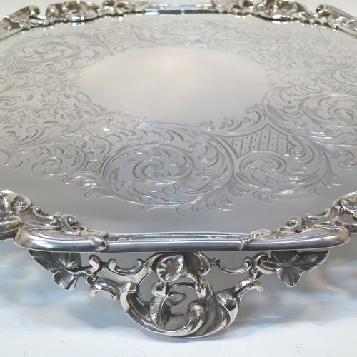 A very pretty Antique Victorian Silver Plated large salver, having an applied cast scroll border with floral decoration and piercing, with a ground having hand-engraved floral and scroll decoration surrounding a central vacant round cartouche, and all sitting on three cast scroll  feet. Made (poss.) by James Dixon And Sons of Sheffield in ca. 1860. The dimensions of this fine hand-made antique silver-plated salver are diameter 48 cms (19 inches), and height 5 cms (2 inches).  