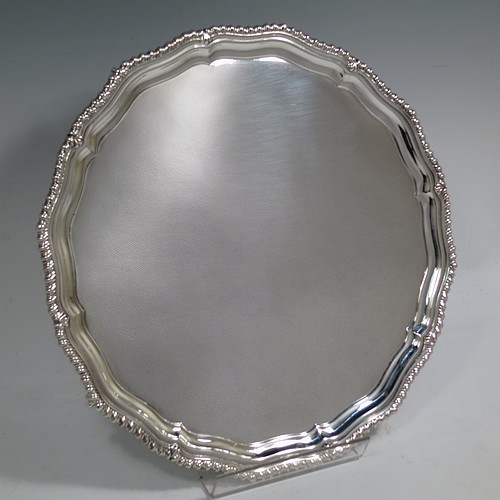 A very handsome Sterling Silver salver, having a round body, with a plain burnished ground, an applied shaped gadroon border, and sitting on four cast claw and ball feet. Made by the Barker Brothers of Birmingham in 1937. The dimensions of this fine hand-made silver salver are diameter 31 cms (12.25 inches), and it weighs approx. 1,040g (33.5 troy ounces).    