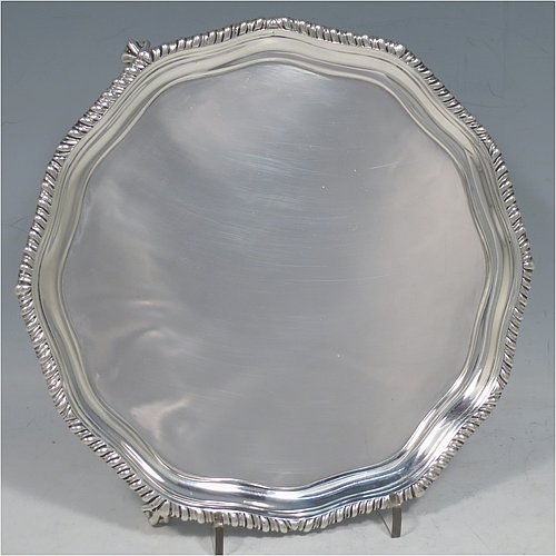 An Antique Victorian Sterling Silver salver, having a shaped gadroon border, a plain ground, and sitting on three cast claw and ball feet. Made by Thomas Edward Harwood of London in 1877. The dimensions of this fine hand-made silver salver are diameter 19 cms (7.5 inches), and it weighs approx. 295g (9.5 troy ounces).   