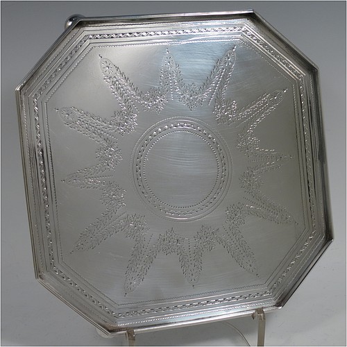 A very handsome and unusual Antique Victorian Sterling silver salver, having an octagonal body, a hand-engraved ground with floral swags and bands of bright-cut decoration, an applied reeded gallery border, and sitting on three cast cushion ball feet. Made by the Barnard Brothers of London in 1897. The dimensions of this fine hand-made antique salver are 21 cms (8.25 inches) square, height 2.5 cms (1 inch), and it weighs approx. 574g (18.5 troy ounces).    