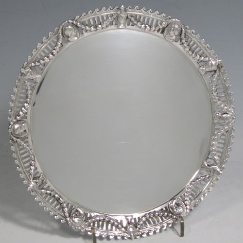 Antique Victorian sterling silver salver, having a plain ground, with an applied hand-chased and pierced border with neoclassical design showing swags, urns, portraits, and a wave-style border, and all sitting on three cast and scroll feet. Made by John Figg of London in 1873. The dimensions of this fine hand-made silver salver are diameter 18 cms (7 inches), and it weighs approx. 244g (7.8 troy ounces).   