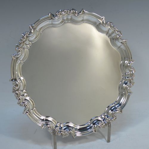 A handsome Antique Sterling Silver round salver, having a plain burnished ground, an applied scroll and floral  border, and sitting on three cast scroll feet. Made by William Hutton of Sheffield in 1917. The dimensions of this fine hand-made antique silver salver are diameter 20 cms (8 inches), and it weighs approx. 340g (11 troy ounces).  