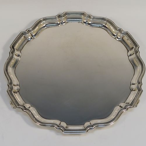 An elegant Sterling Silver round salver, having a plain burnished ground, an applied Chippendale border, and sitting on three cast scroll feet. This handsome silver salver was made by the Barker Brothers of Birmingham in 1923. The dimensions of this fine hand-made silver salver are diameter 20 cms (8 inches), and it weighs approx. 350g (11.3 troy ounces).   