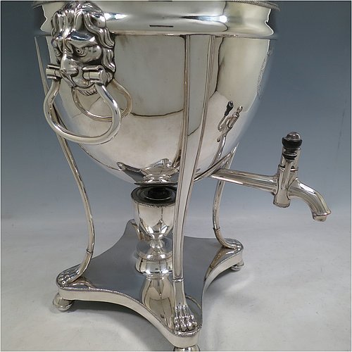 An Antique Georgian Old Sheffield plated urn-style samovar having a plain round body with applied gadroon borders, a band of hand-engraved floral decoration, and cast lion-mask handles. Having a lift-off lid with ball finial, a spigot with wooden finial, and all sitting on four lions-paw feet with a base that includes a removable burner and four ball feet. Made in ca. 1800. The dimensions of this fine hand-made Old Sheffield silver plated samovar are height 48 cms (19 inches), width 26 cms (10 inches), and depth incl. spigot 28 cms (11 inches).   