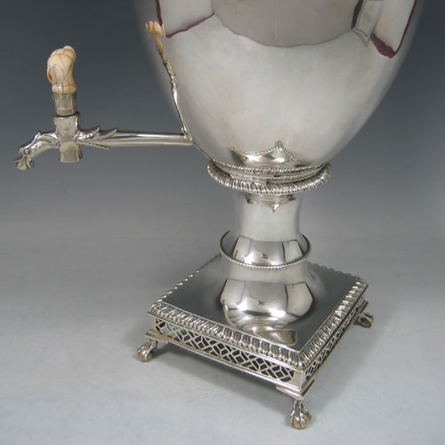 Antique Georgian sterling silver samovar, having a plain ovoid body, with pull-off lid and finial, two side-handles, a spigot with bone handle, with gadroon-edge borders, and all sitting on a pedestal foor with a pierced gallery square base and four claw and ball feet. Please note that this piece has a very unusual heating mechanism where the main body detaches from the foot allowing for the insertion of a heated piece of pig-iron. Made by Ebenezer Coker of London in 1772. The dimensions of this fine hand-made silver samovar are height 46 cms (18 inches), width 24 cms (9.5 inches), and it weighs approx. 1,874g (60.5 troy ounces). 