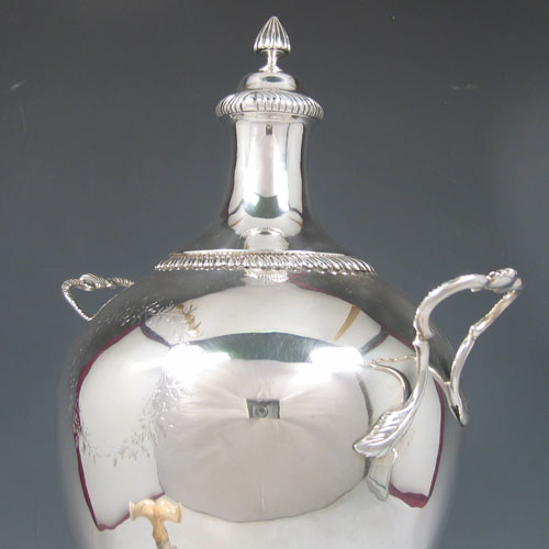 Antique Georgian sterling silver samovar, having a plain ovoid body, with pull-off lid and finial, two side-handles, a spigot with bone handle, with gadroon-edge borders, and all sitting on a pedestal foor with a pierced gallery square base and four claw and ball feet. Please note that this piece has a very unusual heating mechanism where the main body detaches from the foot allowing for the insertion of a heated piece of pig-iron. Made by Ebenezer Coker of London in 1772. The dimensions of this fine hand-made silver samovar are height 46 cms (18 inches), width 24 cms (9.5 inches), and it weighs approx. 1,874g (60.5 troy ounces). 