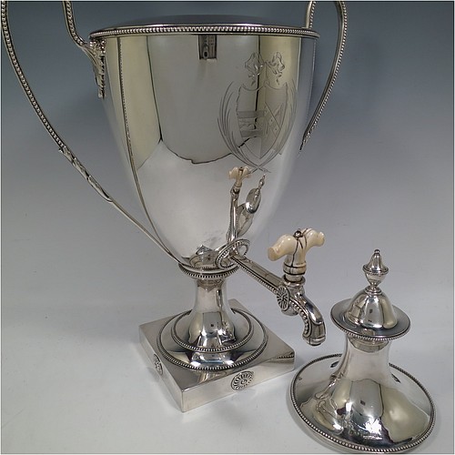 A very handsome Antique Georgian Neoclassical style Sterling Silver samovar, having a plain urn-shaped body, with pull-off lid and finial, two side-handles, an original spigot with bone handle, all with applied bead-edged borders, and all sitting on a pedestal foot with a square base. Please note that this piece has an unusual heating mechanism where the main body detaches from the foot allowing for the insertion of a heated piece of pig-iron. Made by John Denziloe of London in 1783. The dimensions of this fine hand-made antique silver samovar are height 52 cms (20.5 inches), width 33 cms (13 inches), and it weighs approx. 3,112g (100 troy ounces). Please note that this item is crested.  