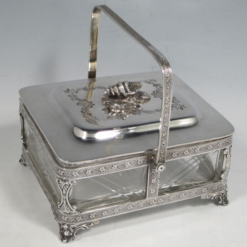 Antique Victorian silver plated sardine dish, having a rectangular body with rounded corners, a cut-crystal liner sitting in a frame which has chased ivy-work, a lift-off lid with cast conch shell finial, a floral swing handle, and all sitting on four cast foliate feet. Made by Walker and Hall of Sheffield in ca. 1880. The dimenions of this fine hand-made silver-plated sardine dish are length 14 cms (5.5 inches), width 12 cms (4.75 inches), and height (excluding handles) 8 cms (3 inches).