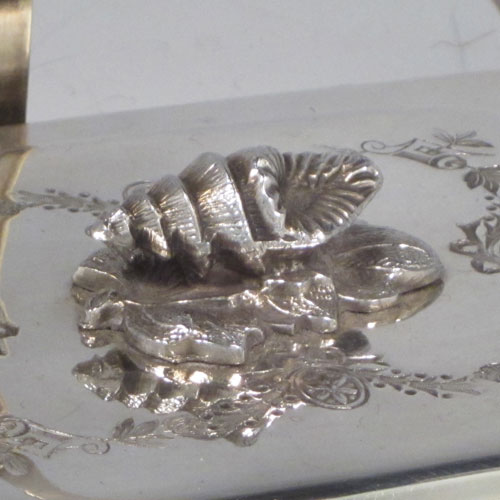 Antique Victorian silver plated sardine dish, having a rectangular body with rounded corners, a cut-crystal liner sitting in a frame which has chased ivy-work, a lift-off lid with cast conch shell finial, a floral swing handle, and all sitting on four cast foliate feet. Made by Walker and Hall of Sheffield in ca. 1880. The dimenions of this fine hand-made silver-plated sardine dish are length 14 cms (5.5 inches), width 12 cms (4.75 inches), and height (excluding handles) 8 cms (3 inches).