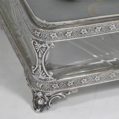 Antique Victorian silver plated sardine dish, having a rectangular body with rounded corners, a cut-crystal liner sitting in a frame which has chased ivy-work, a lift-off lid with cast conch shell finial, a floral swing handle, and all sitting on four cast foliate feet. Made by Walker and Hall of Sheffield in ca. 1880. The dimenions of this fine hand-made silver-plated sardine dish are length 14 cms (5.5 inches), width 12 cms (4.75 inches), and height (excluding handles) 8 cms (3 inches).