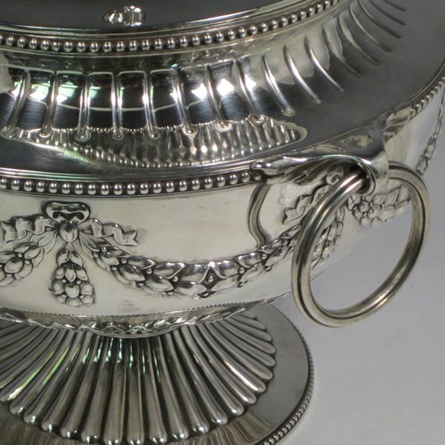 Antique Victorian sterling silver suite of soup and sauce tureens with covers, having round bodies with bead-edged borders, with hand-chased neoclassical style decoration, lift-off lids with anthemion leaves and cast floral finials, side  handles with attached rings, and all sitting on pedestal feet. Made by Robert Hennell II of London in 1872. The dimensions of the fine larger silver tureen are height 27 cms (10.5 inches), diameter length 23 cms (9 inches), with a total weight of approx. 2,356g (76 troy ounces). Please note that these items are crested in one cartouche. 