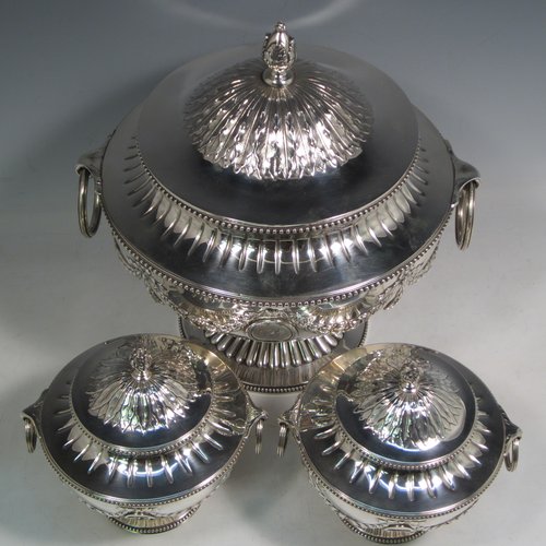 Antique Victorian sterling silver suite of soup and sauce tureens with covers, having round bodies with bead-edged borders, with hand-chased neoclassical style decoration, lift-off lids with anthemion leaves and cast floral finials, side  handles with attached rings, and all sitting on pedestal feet. Made by Robert Hennell II of London in 1872. The dimensions of the fine larger silver tureen are height 27 cms (10.5 inches), diameter length 23 cms (9 inches), with a total weight of approx. 2,356g (76 troy ounces). Please note that these items are crested in one cartouche. 