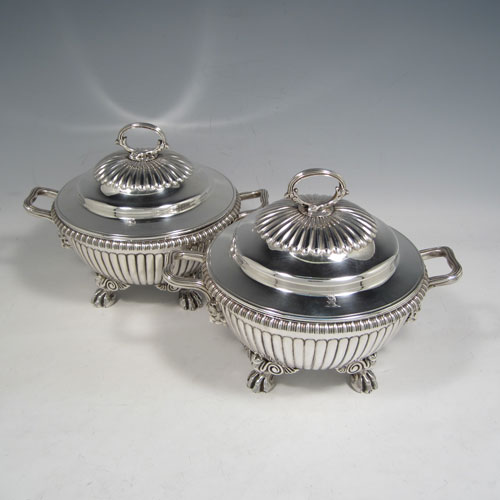 Antique Georgian sterling silver pair of sauce tureens, having round baluster bodies with hand-chased fluted decoration, lift-off lids with matching fluting and asparagus style loop handles, with reeded and lion-mask side-handles, and sitting on four cast lions-paw feet. Made by Emes and Barnard of London in 1810. The dimensions of these fine pair of hand-made silver sauce tureens are height 15 cms (6 inches), diameter 16 cms (6.25 inches), and they weigh a total of approx. 1,676g (54 troy ounces).