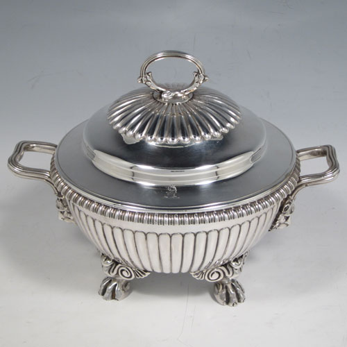 Antique Georgian sterling silver pair of sauce tureens, having round baluster bodies with hand-chased fluted decoration, lift-off lids with matching fluting and asparagus style loop handles, with reeded and lion-mask side-handles, and sitting on four cast lions-paw feet. Made by Emes and Barnard of London in 1810. The dimensions of these fine pair of hand-made silver sauce tureens are height 15 cms (6 inches), diameter 16 cms (6.25 inches), and they weigh a total of approx. 1,676g (54 troy ounces).