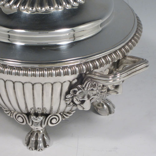 Antique Georgian sterling silver pair of sauce tureens, having round baluster bodies with hand-chased fluted decoration, lift-off lids with matching fluting and asparagus style loop handles, with reeded and lion-mask side-handles, and sitting on four cast lions-paw feet. Made by Emes and Barnard of London in 1810. The dimensions of these fine pair of hand-made silver sauce tureens are height 15 cms (6 inches), diameter 16 cms (6.25 inches), and they weigh a total of approx. 1,676g (54 troy ounces).