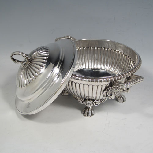 Antique Georgian sterling silver pair of sauce tureens, having round baluster bodies with hand-chased fluted decoration, lift-off lids with matching fluting and asparagus style loop handles, with reeded and lion-mask side-handles, and sitting on four cast lions-paw feet. Made by Emes and Barnard of London in 1810. The dimensions of these fine pair of hand-made silver sauce tureens are height 15 cms (6 inches), diameter 16 cms (6.25 inches), and they weigh a total of approx. 1,676g (54 troy ounces).