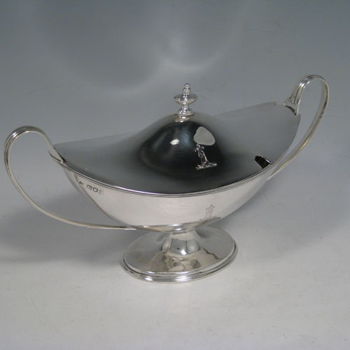 Antique Edwardian sterling silver sauce tureen, having a neoclassical boat-shaped body with reeded border, a lift-off cover with urn finial, two loop handles, all sitting on a pedestal foot. Made by Thomas Bradbury of London in 1904. Height 13 cms (5 inches), length 24 cms (9.5 inches), width 10 cms (4 inches). Total weight approx. 375g (12.1 troy ounces).