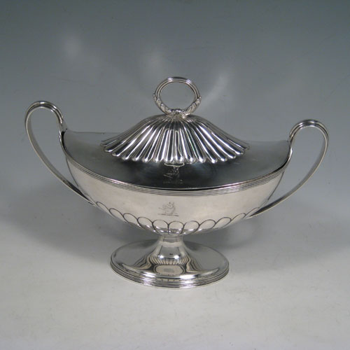 Antique Georgian sterling silver sauce tureen, having a neoclassical boat-shaped body with reeded borders and hand-chased half-fluted decoration, a lift-off cover with loop handle finial, all sitting on a pedestal foot. Made by Henry Chawner of London in 1795. Height 17 cms (6.75 inches), length 24 cms (9.5 inches), width 10 cms (4 inches). Total weight approx. 561g (18.1 troy ounces). Please note that this item is crested.