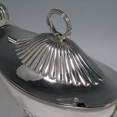 Antique Georgian sterling silver sauce tureen, having a neoclassical boat-shaped body with reeded borders and hand-chased half-fluted decoration, a lift-off cover with loop handle finial, all sitting on a pedestal foot. Made by Henry Chawner of London in 1795. Height 17 cms (6.75 inches), length 24 cms (9.5 inches), width 10 cms (4 inches). Total weight approx. 561g (18.1 troy ounces). Please note that this item is crested.