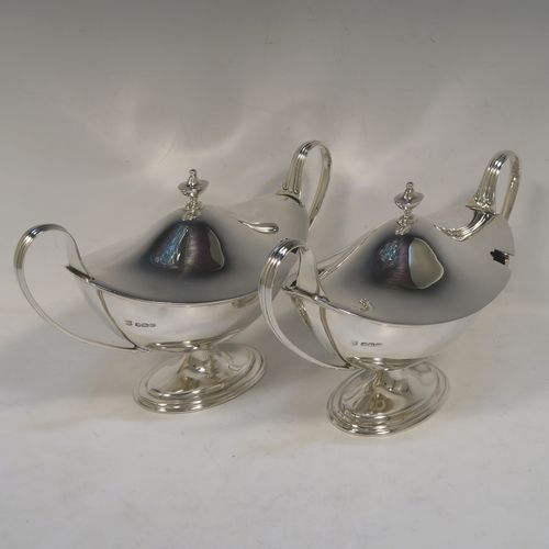 A very elegant Sterling Silver pair of sauce tureens with covers, having plain oval neoclassical boat-shaped bodies with applied reeded borders, pull-off lids with cast finials,  with reeded loop side-handles, and all sitting on pedestal feet. These beautiful silver sauce tureens were made by Thomas Bradbury of Sheffield in 1931. The dimensions of this fine hand-made silver2 pair of sauce tureens are height 13.5 cms (5.5 inches), length 23 cms (9 inches), width 10 cms (4 inches), with a total weight of approx. 853g (27.5 troy ounces).    