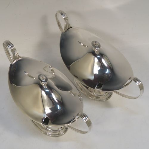 A very elegant Sterling Silver pair of sauce tureens with covers, having plain oval neoclassical boat-shaped bodies with applied reeded borders, pull-off lids with cast finials,  with reeded loop side-handles, and all sitting on pedestal feet. These beautiful silver sauce tureens were made by Thomas Bradbury of Sheffield in 1931. The dimensions of this fine hand-made silver2 pair of sauce tureens are height 13.5 cms (5.5 inches), length 23 cms (9 inches), width 10 cms (4 inches), with a total weight of approx. 853g (27.5 troy ounces).    