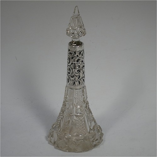 An Antique Edwardian Sterling Silver and hand-cut crystal table scent bottle, having a hand-cut round body with tapering sides, a hand-chased silver mount with floral decoration, an original crystal stopper, and all sitting on a star-cut flat base. Made by C. C. May and Sons of Birmingham in 1906. The dimensions of this fine hand-made antique silver and crystal scent bottle are height 17 cms (6.6 inches), and diameter at base 6.5 cms (2.5 inches). 