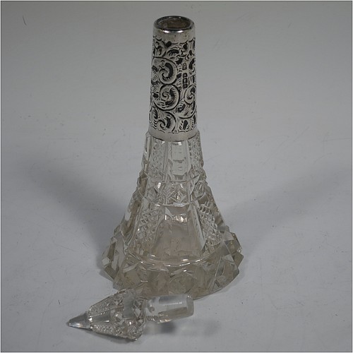 An Antique Edwardian Sterling Silver and hand-cut crystal table scent bottle, having a hand-cut round body with tapering sides, a hand-chased silver mount with floral decoration, an original crystal stopper, and all sitting on a star-cut flat base. Made by C. C. May and Sons of Birmingham in 1906. The dimensions of this fine hand-made antique silver and crystal scent bottle are height 17 cms (6.6 inches), and diameter at base 6.5 cms (2.5 inches). 