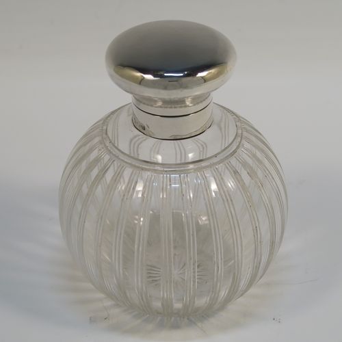 An elegant Antique Sterling Silver and hand-cut crystal large table scent bottle, having a plain round mount, a plain round hinged lid, an internal stopper, and a hand-cut crystal round main body with reeded decoration, and sitting on a flat base with a star-cut. This handsome antique silver and crystal scent bottle was made by William Comyns of Birmingham in 1913. The dimensions of this fine hand-made antique silver and crystal scent bottle are height 10 cms (4 inches), and diameter 9 cms (3.5 inches).   