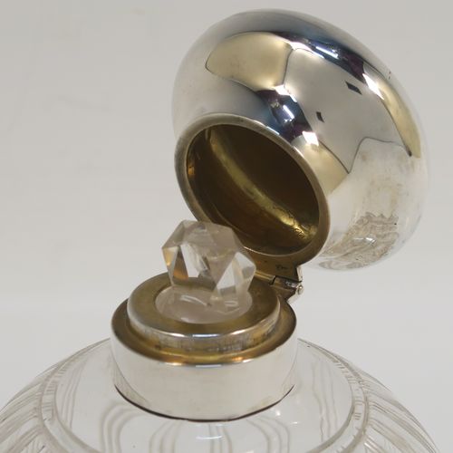 An elegant Antique Sterling Silver and hand-cut crystal large table scent bottle, having a plain round mount, a plain round hinged lid, an internal stopper, and a hand-cut crystal round main body with reeded decoration, and sitting on a flat base with a star-cut. This handsome antique silver and crystal scent bottle was made by William Comyns of Birmingham in 1913. The dimensions of this fine hand-made antique silver and crystal scent bottle are height 10 cms (4 inches), and diameter 9 cms (3.5 inches).   