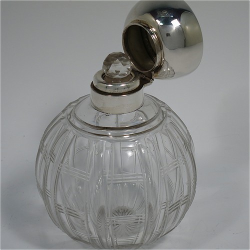 An Antique Sterling Silver and hand-cut crystal large table scent bottle, having a plain round mount, a hinged lid with an applied floral border and bands of engine-turned engraved decoration, an internal stopper, and a hand-cut crystal round main body with geometrical decoration. Made by Synyer and Beddoes of Birmingham in 1915. The dimensions of this fine hand-made antique silver and crystal scent bottle are height 11.5 cms (4.5 inches), and diameter 8 cms (3.25 inches).    