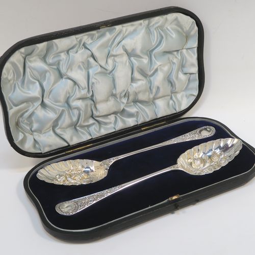 A very pretty pair of Antique Victorian Sterling Silver berry serving spoons, having hand-chased handles with floral decoration, and hand-chased bowls with fluted and fruit decoration, all in their original light blue satin and dark blue velvet-lined presentation box. These beautiful silver serving spoons were made by William Hutton and Sons of London in 1893. The dimensions of this fine hand-made pair of antique silver berry spoons are length 22cms (8.75 inches), and they weigh a total of approx. 146g (4.7 troy ounces).   