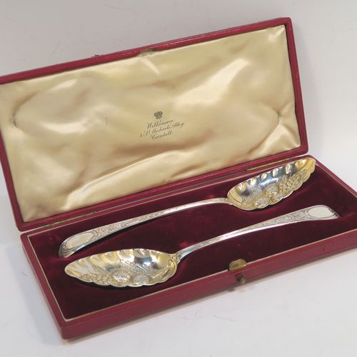 A very pretty pair of Antique Georgian Sterling Silver berry serving spoons, having hand-chased handles with floral decoration, and hand-chased gold-gilt bowls with fluted and fruit decoration, all in a cream satin and maroon velvet-lined presentation box. These beautiful silver serving spoons were made by Smith and Fern of London in 1795. The dimensions of this fine hand-made pair of antique silver berry spoons are length 22cms (8.75 inches), and they weigh a total of approx. 129g (4.2 troy ounces).   