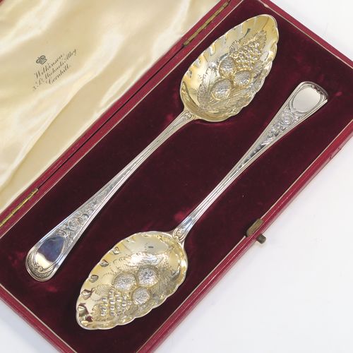 A very pretty pair of Antique Georgian Sterling Silver berry serving spoons, having hand-chased handles with floral decoration, and hand-chased gold-gilt bowls with fluted and fruit decoration, all in a cream satin and maroon velvet-lined presentation box. These beautiful silver serving spoons were made by Smith and Fern of London in 1795. The dimensions of this fine hand-made pair of antique silver berry spoons are length 22cms (8.75 inches), and they weigh a total of approx. 129g (4.2 troy ounces).   