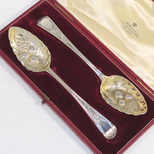 A very pretty pair of Antique Georgian Sterling Silver berry serving spoons, having hand-chased handles with floral decoration, and hand-chased gold-gilt bowls with fluted and fruit decoration, all in a cream satin and maroon velvet-lined presentation box. These beautiful silver serving spoons were made by Smith and Fern of London in 1795. The dimensions of this fine hand-made pair of antique silver berry spoons are length 22cms (8.75 inches), and they weigh a total of approx. 129g (4.2 troy ounces).   