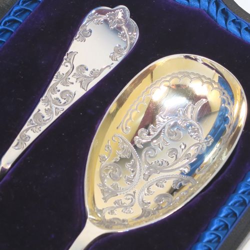 An extremely pretty pair of Antique Victorian Sterling Silver berry serving spoons, having hand-engraved handles and bowls with floral and scroll decoration, the bowls with a gold-gilt wash, and the handles with twisted middle sections, all in their original blue satin and velvet-lined presentation box. These beautiful silver serving spoons were made by the Atkin Brothers of Sheffield in 1900. The dimensions of this fine hand-made pair of antique silver berry spoons are length 21cms (8.3 inches), and they weigh a total of approx. 116g (3.7 troy ounces).  