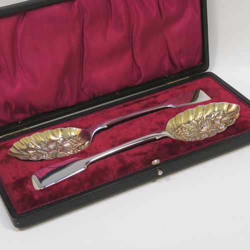 A very pretty pair of Antique Georgian Sterling Silver and gold-gilt berry serving spoons, having  handles in the Fiddle pattern, and gold-gilt hand-chased fluted bowls with fruit decoration, all in their original maroon satin and velvet-lined presentation box. These beautiful antique silver berry serving spoons were made by Aldwinkle and Slater of London in 1894. The dimensions of this fine hand-made pair of antique silver berry spoons are length 23cms (9 inches), and they weigh a total of approx. 143g (4.6 troy ounces).   