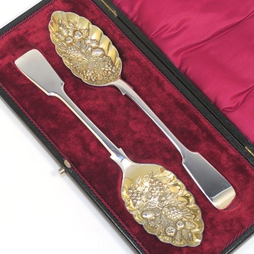 A very pretty pair of Antique Georgian Sterling Silver and gold-gilt berry serving spoons, having  handles in the Fiddle pattern, and gold-gilt hand-chased fluted bowls with fruit decoration, all in their original maroon satin and velvet-lined presentation box. These beautiful antique silver berry serving spoons were made by Aldwinkle and Slater of London in 1894. The dimensions of this fine hand-made pair of antique silver berry spoons are length 23cms (9 inches), and they weigh a total of approx. 143g (4.6 troy ounces).   