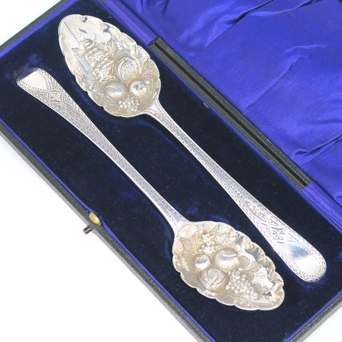 A very pretty pair of Antique Georgian Sterling Silver berry serving spoons, having hand-chased handles with zig-zag and floral decoration, and hand-chased bowls with fruit decoration, all in a dark blue satin and velvet-lined presentation box. These beautiful silver serving spoons were made by George Smith of London in 1774. The dimensions of this fine hand-made pair of antique silver berry spoons are length 21.5cms (8.5 inches), and they weigh a total of approx. 124g (4 troy ounces).   