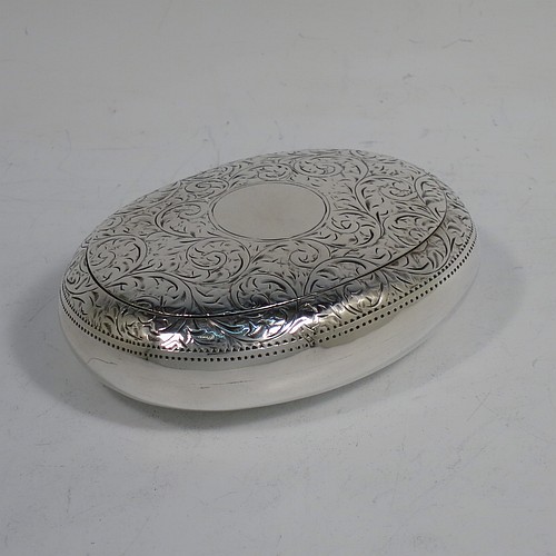 A very pretty Antique Edwardian Sterling Silver tobacco box, having an oval body, with hand-engraved floral and scroll decoration, a vacant cartouche, a squeeze-action sprung hinged lid, and a gold-gilt interior. Made by James Round of Birmingham in 1910. The dimensions of this fine hand-made antique silver tobacco box are length 8 cms (3.25 inches), width 6 cms (2.3 inches), and it weighs approx. 78g (2.5 troy ounces).    