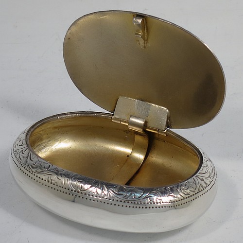 A very pretty Antique Edwardian Sterling Silver tobacco box, having an oval body, with hand-engraved floral and scroll decoration, a vacant cartouche, a squeeze-action sprung hinged lid, and a gold-gilt interior. Made by James Round of Birmingham in 1910. The dimensions of this fine hand-made antique silver tobacco box are length 8 cms (3.25 inches), width 6 cms (2.3 inches), and it weighs approx. 78g (2.5 troy ounces).    