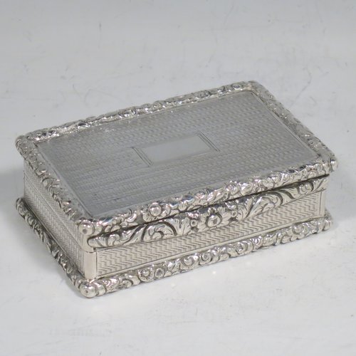 An Antique Georgian Sterling silver large and heavy snuff box, having a rectangular body with engine-turned decoration, with applied cast foliate thumb-piece and borders, and a gold-gilt interior. Made by John Bettridge of Birmingham in 1825. The dimensions of this fine hand-made antique silver snuff box are length 8 cms (3.25 inches), width 5 cms (2 inches), depth 2.5 cms (1.0 inches), and it weighs approx. 156g (5 troy ounces).   