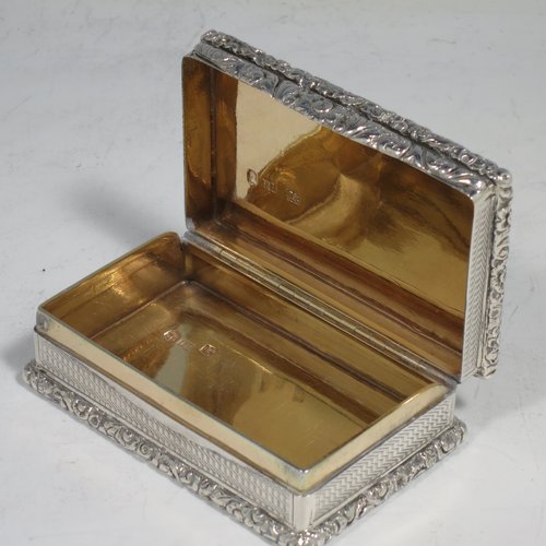 An Antique Georgian Sterling silver large and heavy snuff box, having a rectangular body with engine-turned decoration, with applied cast foliate thumb-piece and borders, and a gold-gilt interior. Made by John Bettridge of Birmingham in 1825. The dimensions of this fine hand-made antique silver snuff box are length 8 cms (3.25 inches), width 5 cms (2 inches), depth 2.5 cms (1.0 inches), and it weighs approx. 156g (5 troy ounces).   