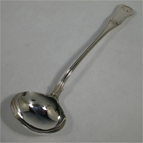 A very handsome and heavy Antique Georgian Sterling Silver soup ladle in the double-struck Kings Hourglass pattern, having a hand-chased shell and hour-glass on the handle, and a plain oval bowl with a shell on the reverse. Made by William Eley of London in 1828. The dimensions of this fine hand-made antique silver soup ladle are length 33 cms (13 inches), and it weighs approx. 270g (8.7 troy ounces).    