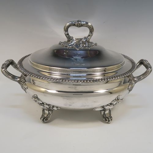 A very handsome Antique Georgian Old Sheffield Plated soup tureen in a Regency style, having an oval plain bellied body with an applied gadroon border, a domed pull-off cover with a cast anthemion leaf handle, with two cast anthemion leaf side handles, and sitting on four cast scroll  feet with floral shoulders. This elegant antique Old Sheffield Plated soup tureen and cover was made in ca. 1815. The dimensions of this fine hand-made antique Old Sheffield soup tureen are length (across handles), width 23.5 cms (9.25 inches), height 25.5 cms (10 inches). Please note that this antique Georgian Regency soup tureen is crested on the cover.   