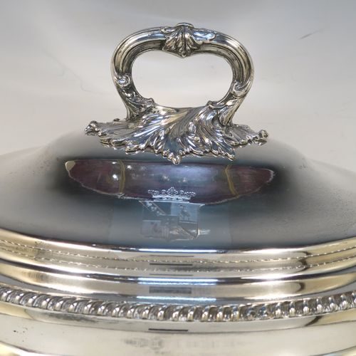 A very handsome Antique Georgian Old Sheffield Plated soup tureen in a Regency style, having an oval plain bellied body with an applied gadroon border, a domed pull-off cover with a cast anthemion leaf handle, with two cast anthemion leaf side handles, and sitting on four cast scroll  feet with floral shoulders. This elegant antique Old Sheffield Plated soup tureen and cover was made in ca. 1815. The dimensions of this fine hand-made antique Old Sheffield soup tureen are length (across handles), width 23.5 cms (9.25 inches), height 25.5 cms (10 inches). Please note that this antique Georgian Regency soup tureen is crested on the cover.   