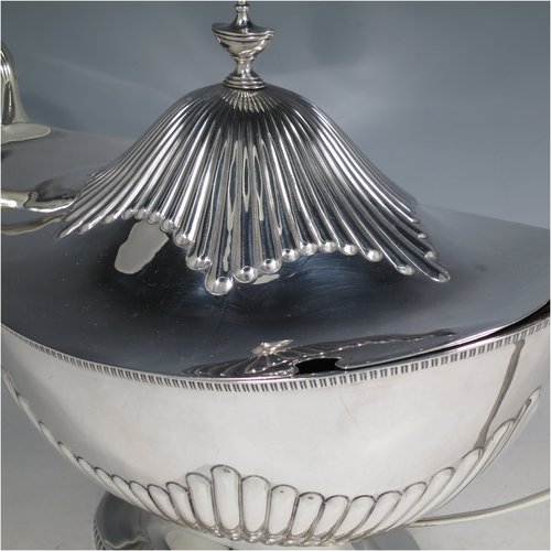 An Antique Edwardian Sterling silver soup tureen, having a pull-off lid with an urn-shaped finial and cut-out slot for a ladle, with hand-chased half-fluted decoration, applied gadroon borders, two reeded scroll side-handles, and all sitting on a pedestal foot. Made by Mappin & Webb of Sheffield in  1905. The dimensions of this fine hand-made antique silver soup tureen and cover are height 25 cms (9.75 inches), length including handles 39.5 cms (15.5 inches), width 21.5 cms (8.5 inches), and it weighs approx. 1,779 (57 troy ounces).   