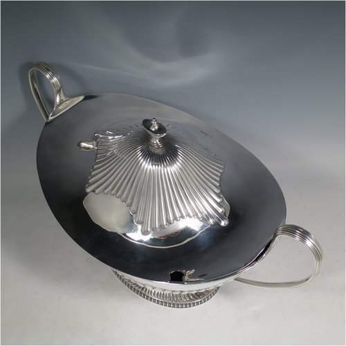 An Antique Edwardian Sterling silver soup tureen, having a pull-off lid with an urn-shaped finial and cut-out slot for a ladle, with hand-chased half-fluted decoration, applied gadroon borders, two reeded scroll side-handles, and all sitting on a pedestal foot. Made by Mappin & Webb of Sheffield in  1905. The dimensions of this fine hand-made antique silver soup tureen and cover are height 25 cms (9.75 inches), length including handles 39.5 cms (15.5 inches), width 21.5 cms (8.5 inches), and it weighs approx. 1,779 (57 troy ounces).   