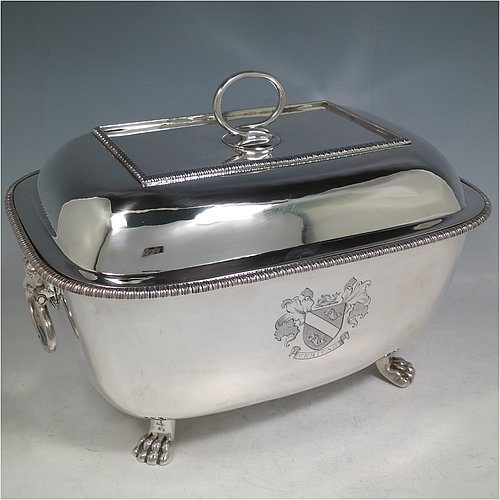 An Antique Georgian Sterling Silver soup tureen, having a plain rectangular body with rounded corners, a pull-off lid cover with an asparagus loop handle, with applied gadroon borders, two cast lion-mask loop side handles, and all sitting on four cast lions-paw feet. Made by William Bennett of London in 1805. The dimensions of this fine hand-made antique silver soup tureen and cover are height 21 cms (8.25 inches), length 28 cms (11 inches), width 20 cms (8 inches), and it weighs approx. 1,860 (60 troy ounces). Please note that this antique soup tureen is crested on one side.